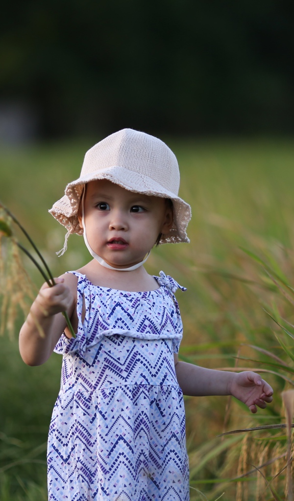 Маленькая девочка азиатка стоит в траве