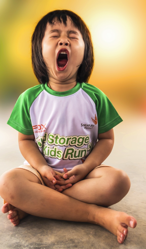 Маленькая девочка азиатка зевает на полу