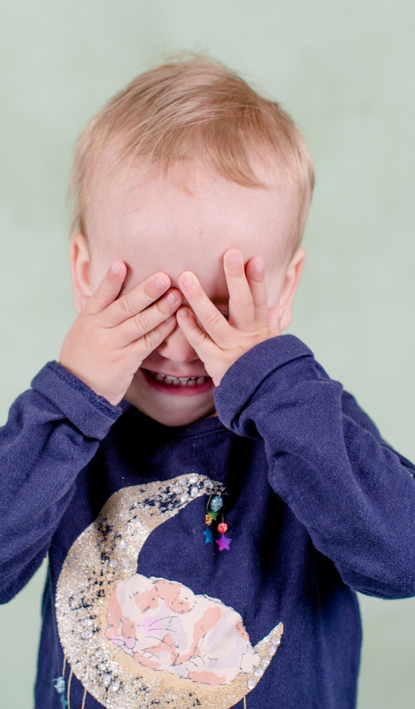 Маленький мальчик закрыл руками лицо 