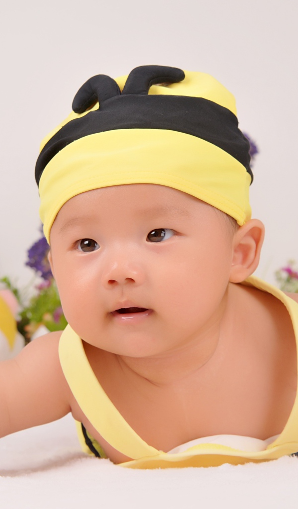 Маленький мальчик в шапке пчелы на сером фоне 