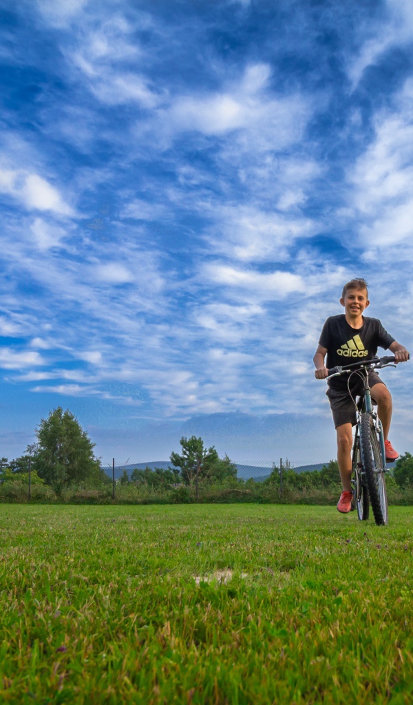 Маленький мальчик катается на велосипеде по полю 
