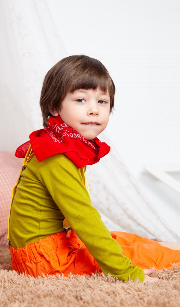 Маленький мальчик сидит на кровати