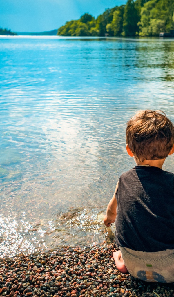 Маленький мальчик кидает камни в воду