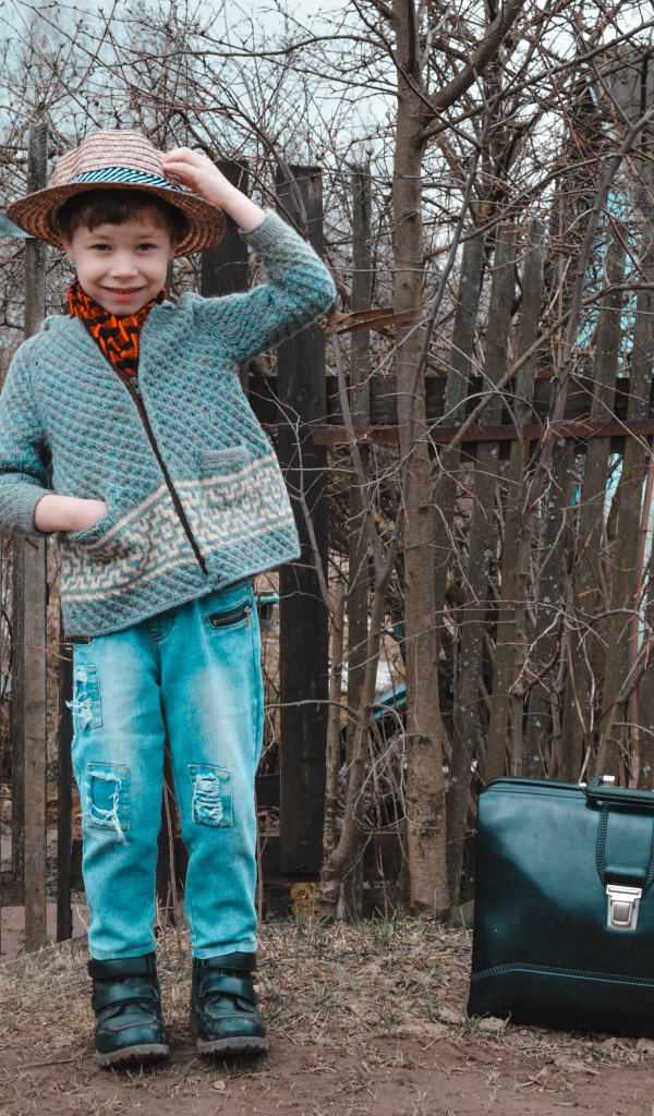 Маленький мальчик с чемоданом у забора