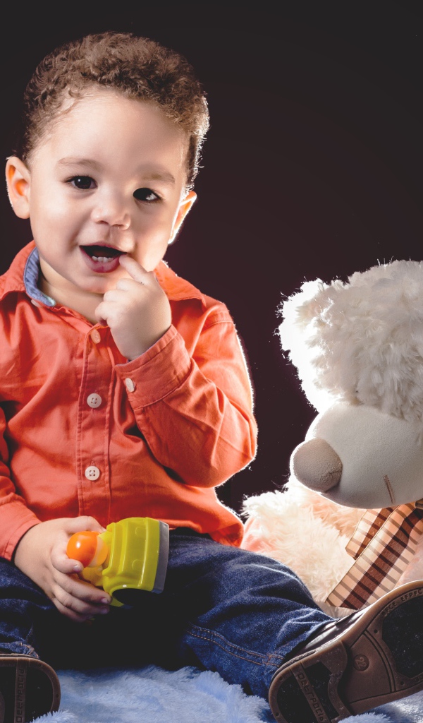 Маленький мальчик с игрушечным медведем на черном фоне