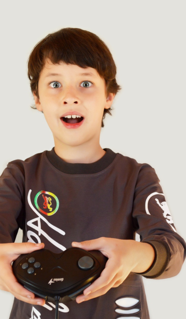 Маленький мальчик с приставкой на сером фоне 