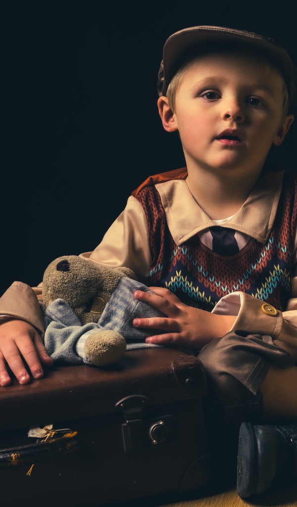 Маленький мальчик с чемоданом и игрушкой