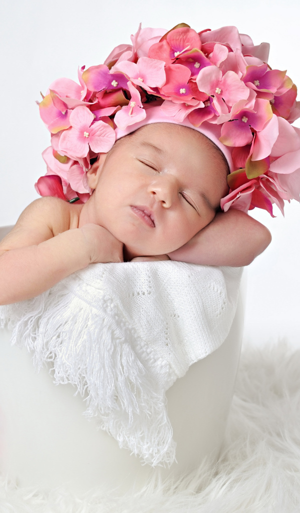 Маленький ребенок в шапке с цветами в горшке 