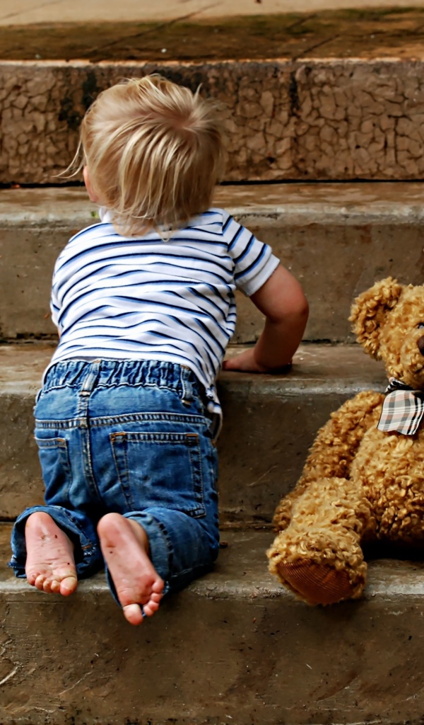 Маленький ребенок с медведем на ступеньках