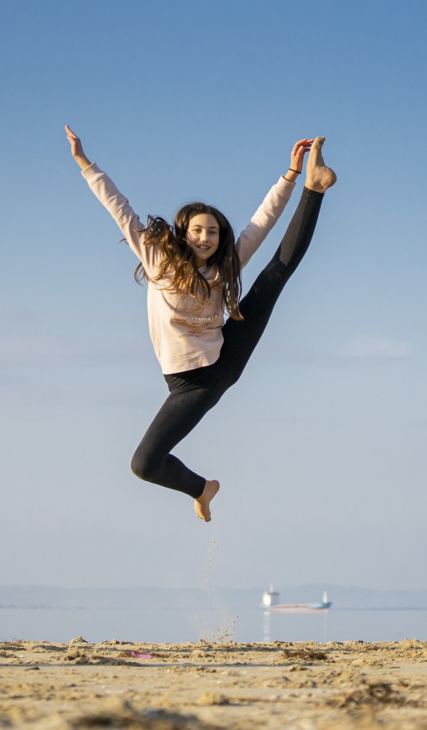 Маленькая девочка гимнастка на песке