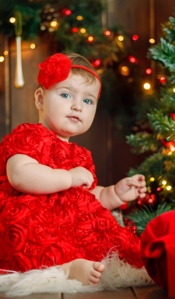 Маленькая девочка в красивом платье у наряженной ели 