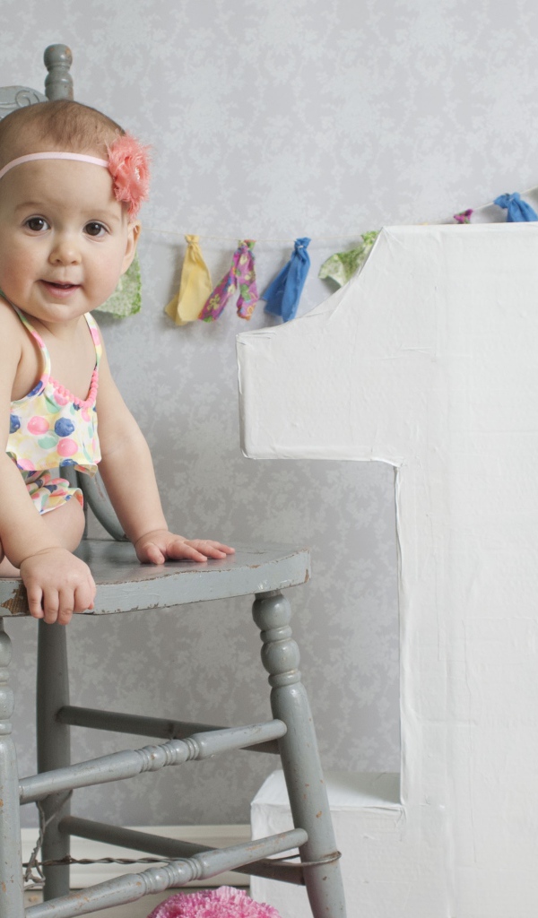 Маленькая девочка в платье на стуле