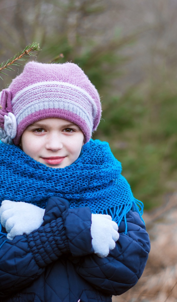 Маленькая девочка в теплой одежде у ели