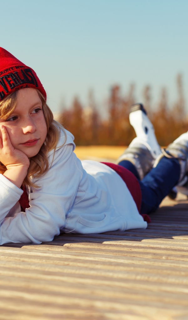 Маленькая девочка лежит на деревянном полу 