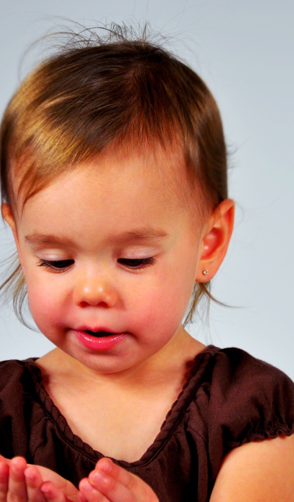 Маленькая девочка смотрит на руки на сером 