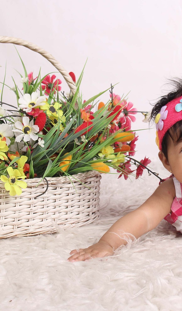 Маленькая девочка рядом с корзиной цветов 