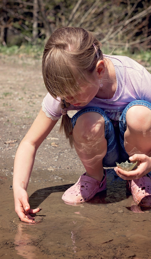 Маленькая девочка играет в луже 