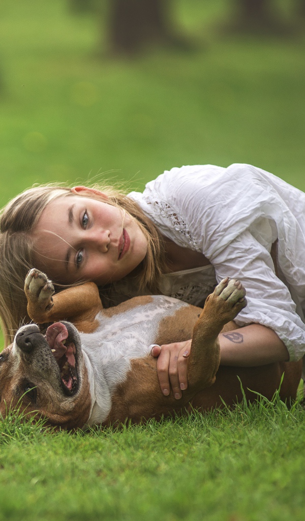 Маленькая девочка играет с собакой на траве летом