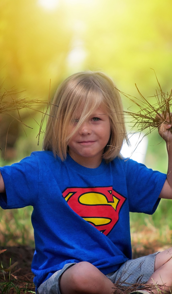 Маленькая девочка сидит на земле с травой