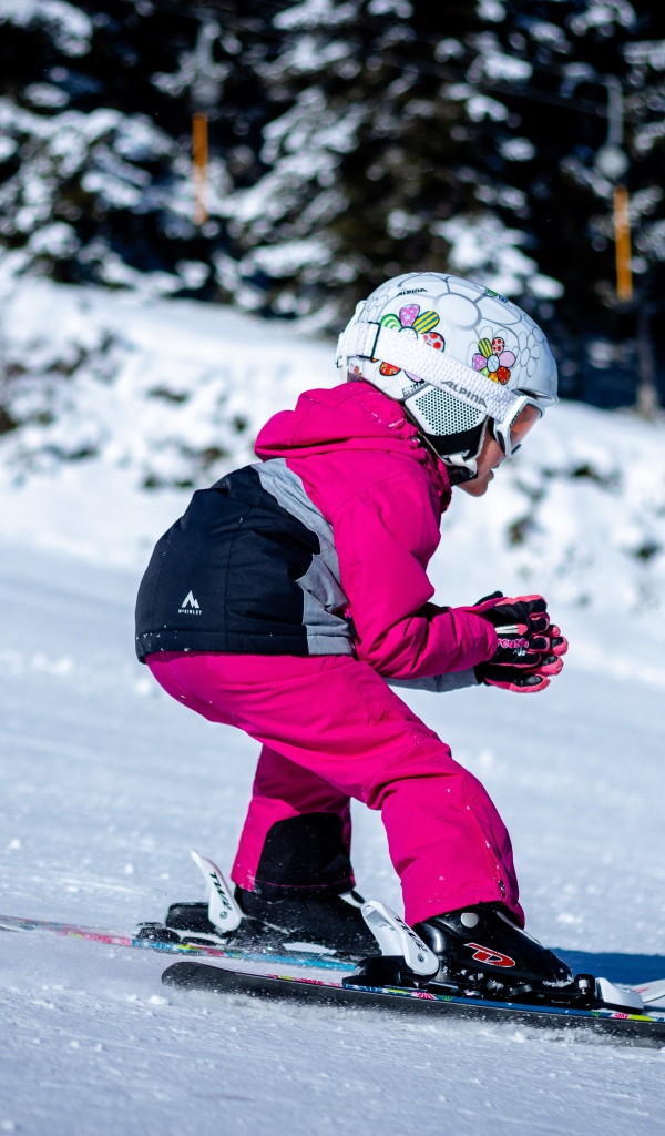 Маленькая девочка едет на лыжах по снегу