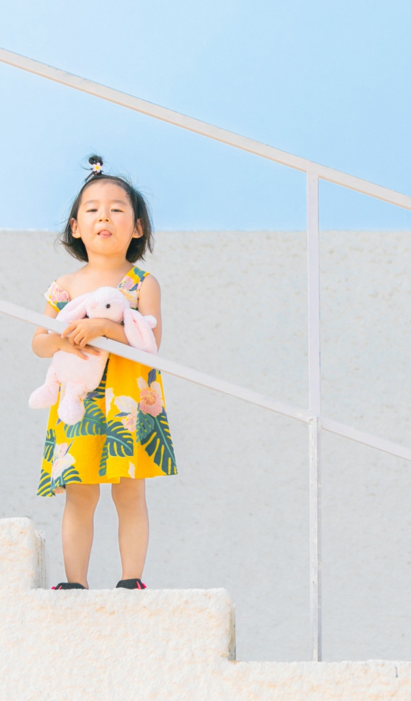 Маленькая девочка с игрушкой на ступеньках 