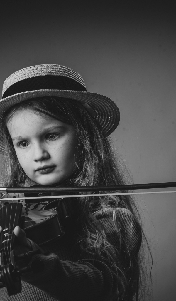 Маленькая девочка со скрипкой в руках на сером фоне