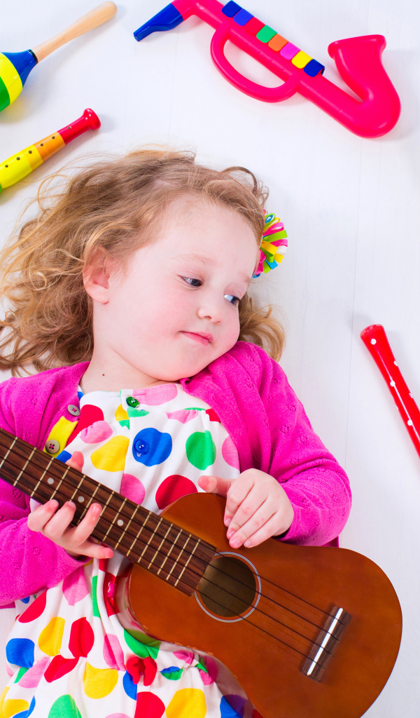 Маленькая девочка с гитарой и игрушечными музыкальными  инструментами 