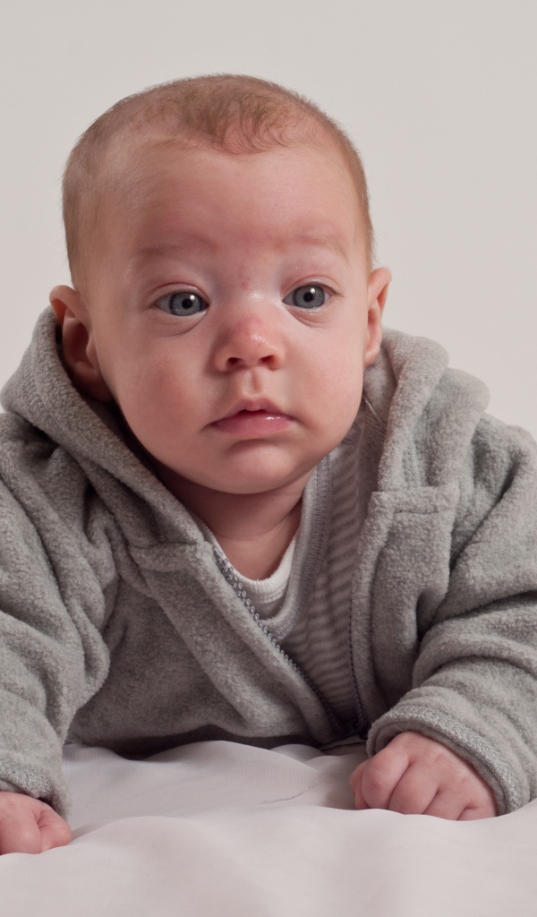 Маленький новорожденный мальчик в сером костюме