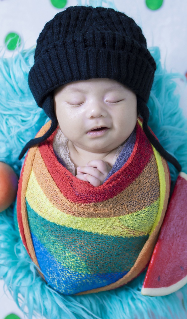 Маленький спящий ребенок в черной шапке 