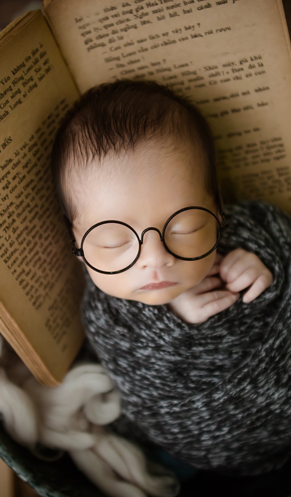 Маленький спящий ребенок в ведре с книгой 