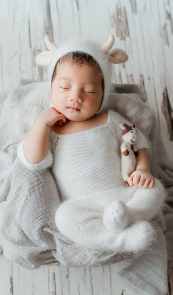 Маленький спящий грудной ребенок в белом костюме