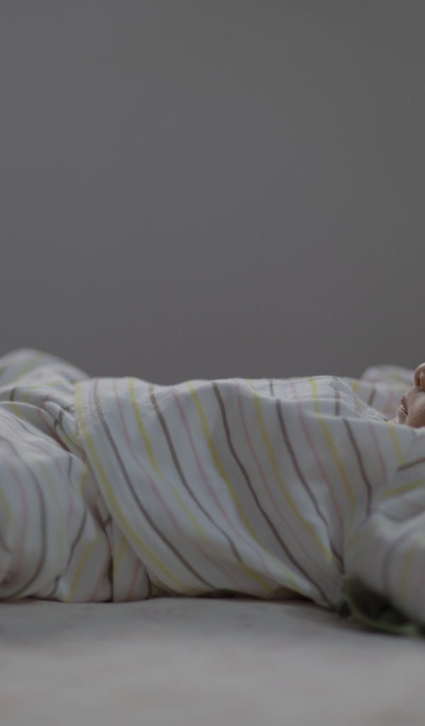 Маленький спящий грудной ребенок на кровати 