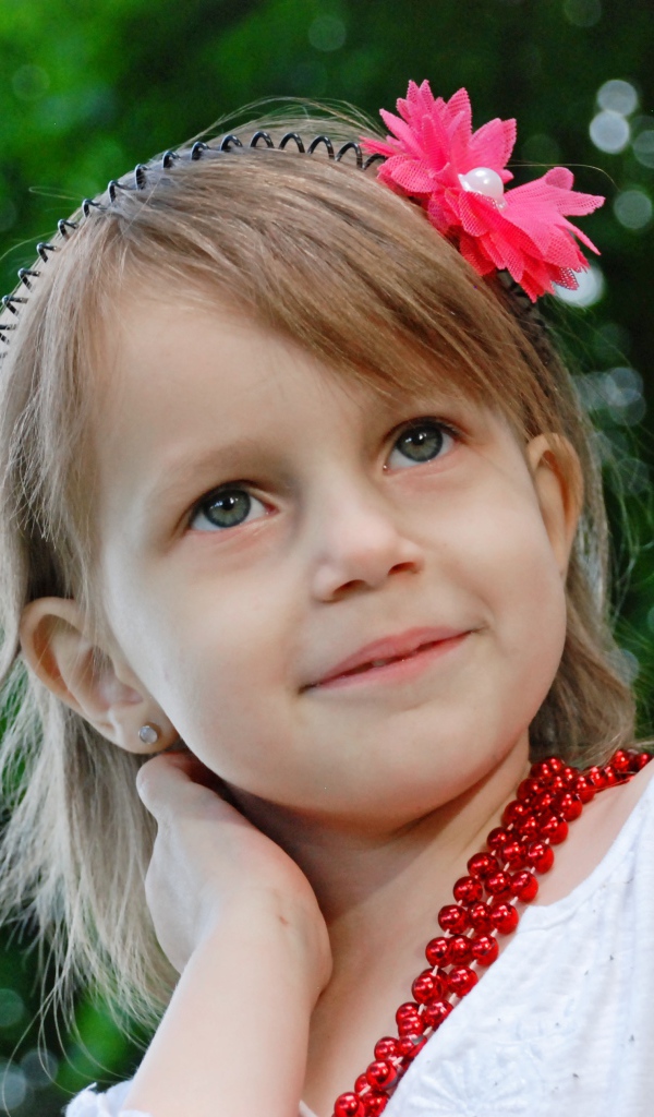 Маленькая улыбающаяся девочка у дерева 