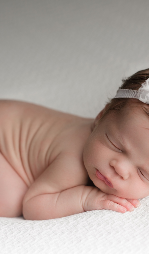 Новорожденная девочка с белой повязкой на голове