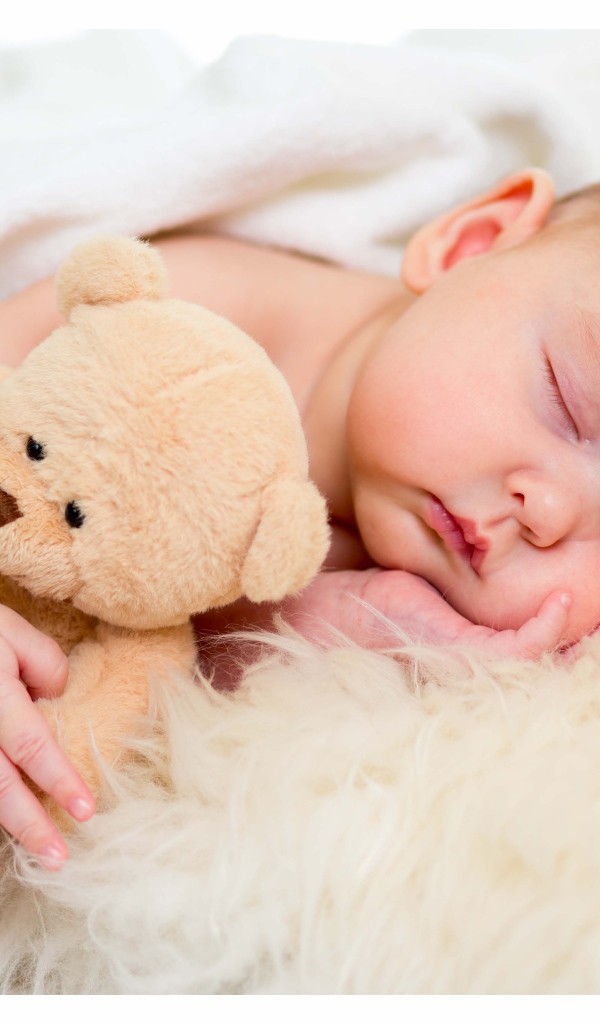 Новорожденный ребенок спит с игрушечным медведем