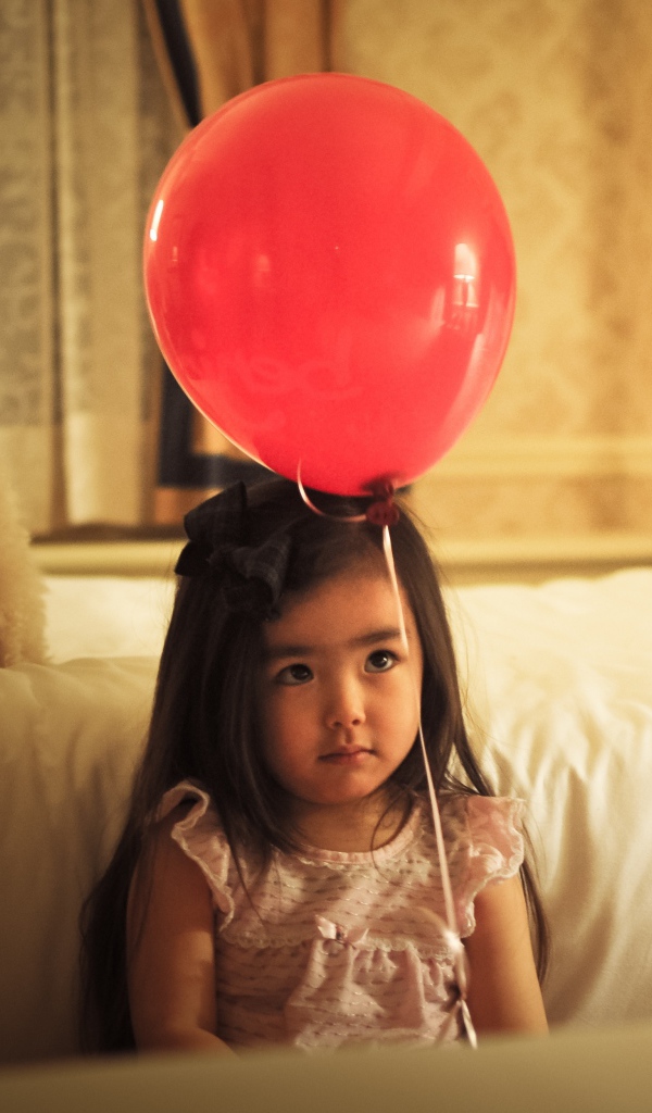 Грустная девочка азиатка с красным шариком