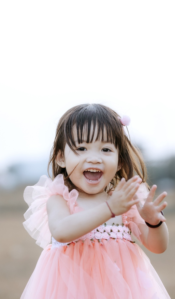 Довольная маленькая девочка в розовом платье 