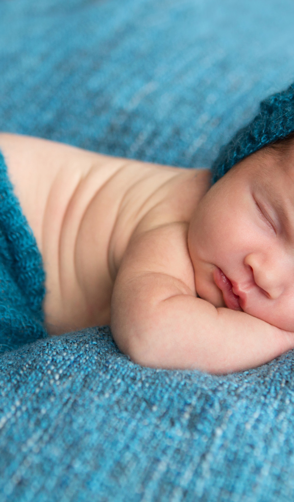 Спящий грудной ребенок лежит на голубом покрывале 