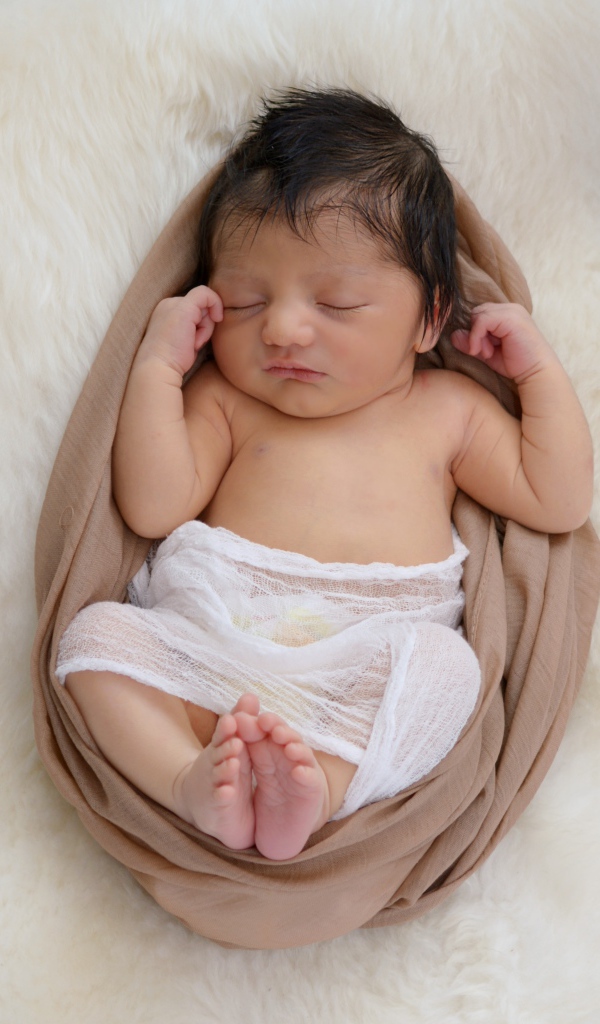 Спящий грудной ребенок на меховом покрывале 