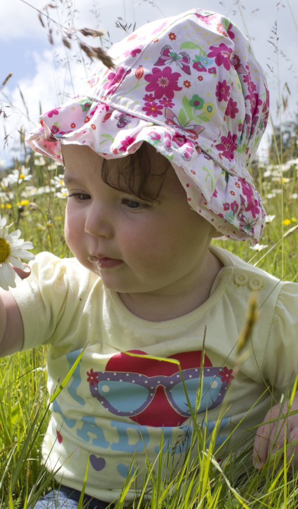 Маленький ребенок в панамке с ромашкой в руке