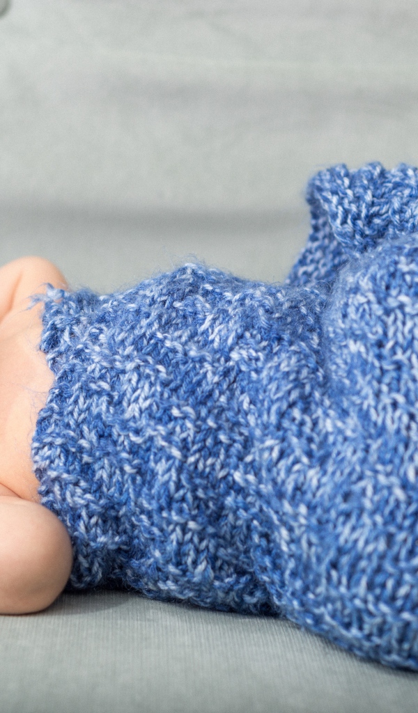 Маленький грудной ребенок в синем вязаном покрывале 