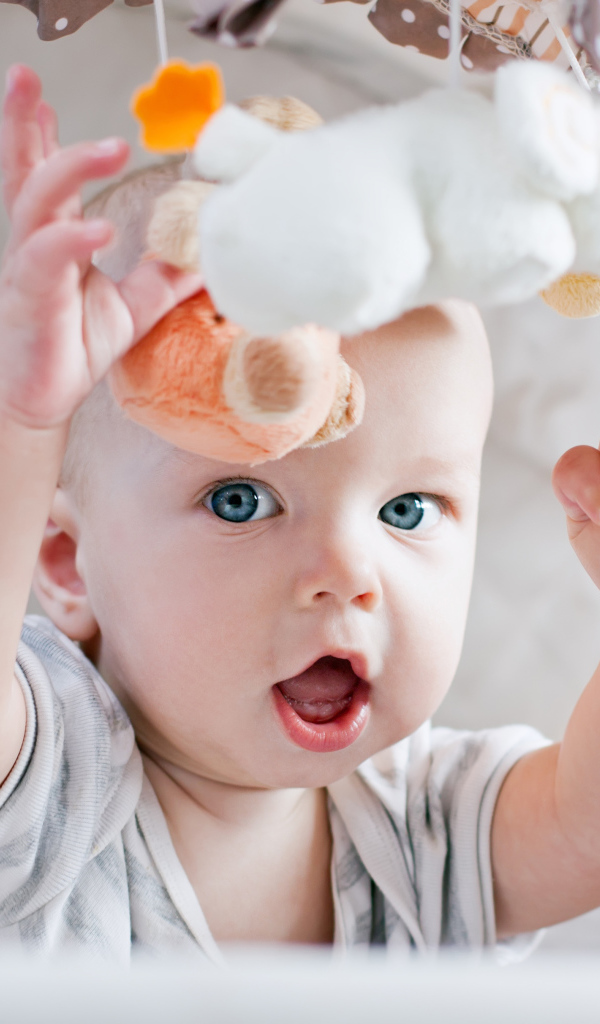 Маленький грудной ребенок в коляске с игрушками 