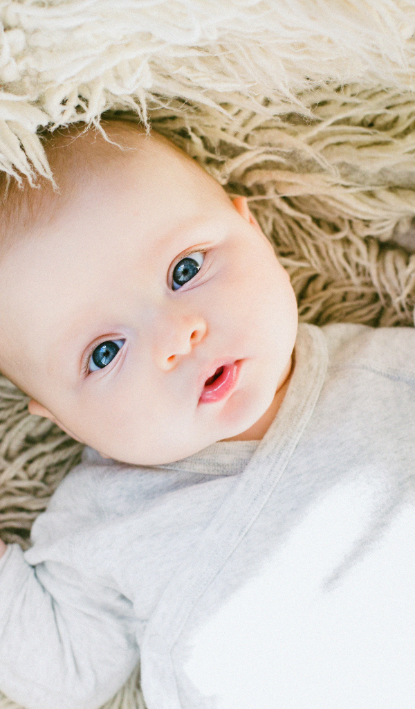 Маленький грудной ребенок на меховом покрывале 