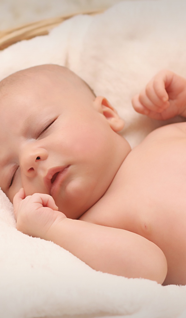 Маленький грудной ребенок спит в корзине 