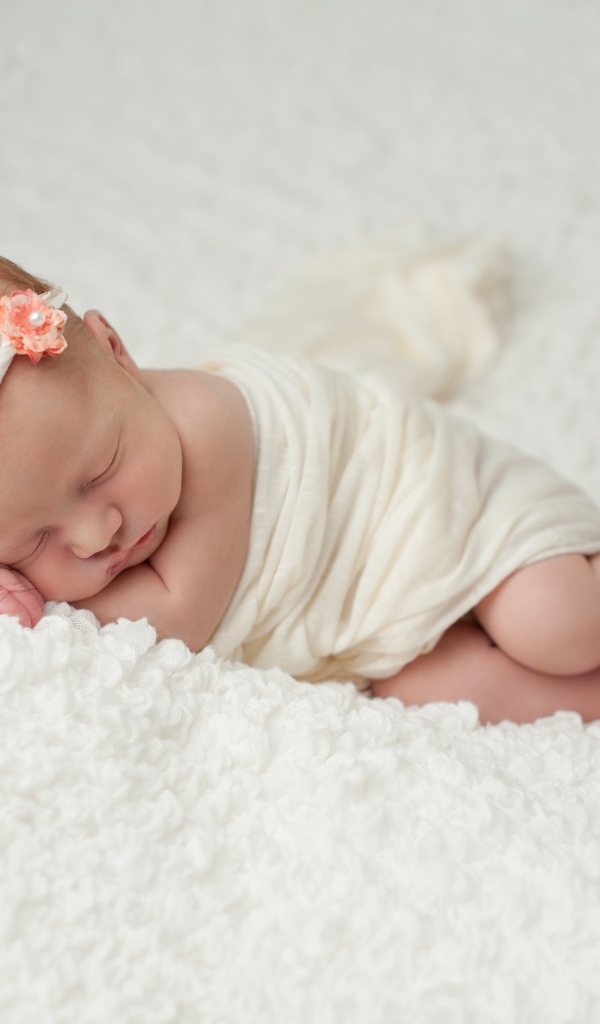 Маленький грудной ребенок спит на белом покрывале 