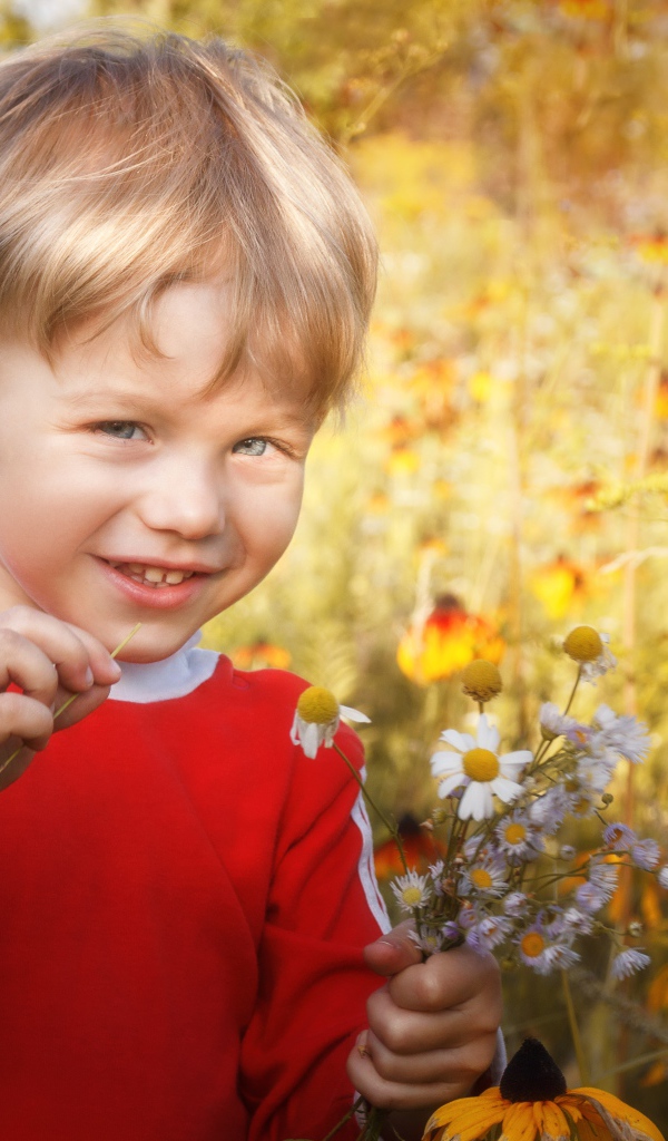 Улыбающийся голубоглазый мальчик с полевыми цветами 
