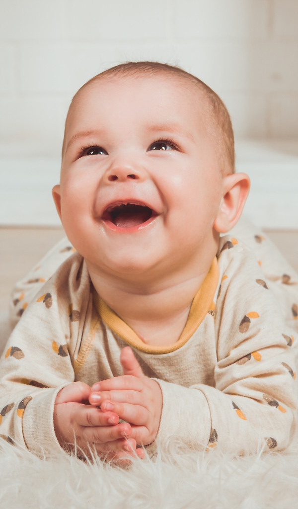 Улыбающийся грудной ребенок лежит на меховом покрывале 