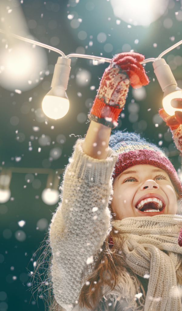 Улыбающаяся девочка вешает лампочки 