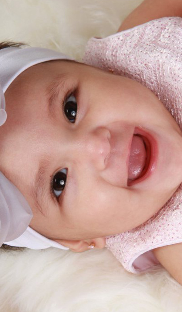 Улыбающаяся девочка в розовом платье с бантом на голове