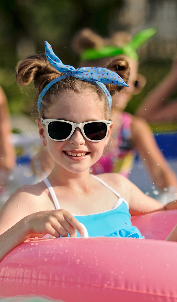 Улыбающаяся девочка со спасательным кругом в бассейне 